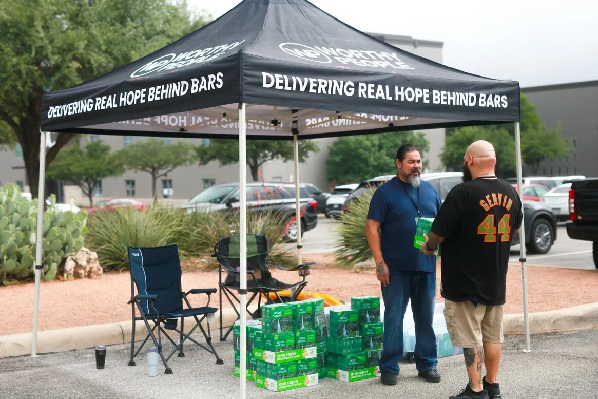 Two men at Worthy People outreach tent with supply boxes