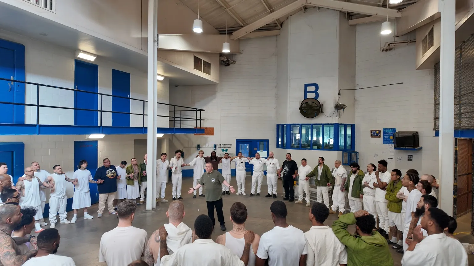 Group of inmates and volunteers gathered inside prison gym