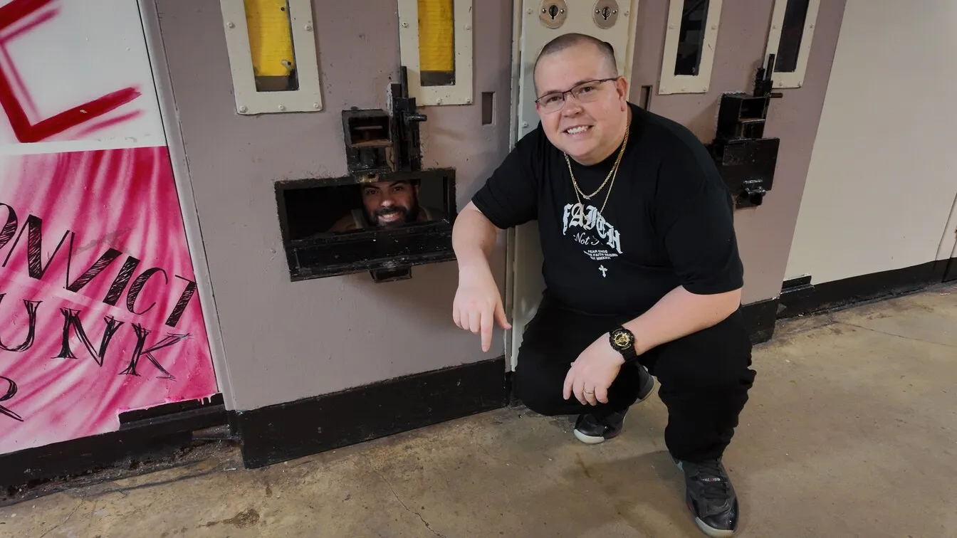 Volunteer kneeling by prison cell door talking to inmate