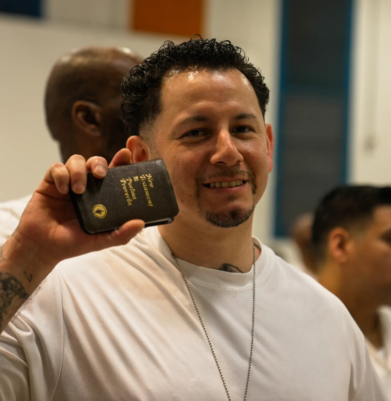 Man holding small Bible smiling in prison chapel