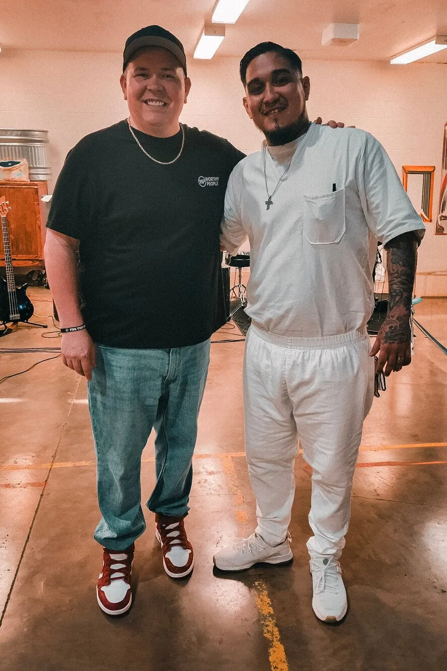 Worthy People volunteer standing with inmate in white uniform