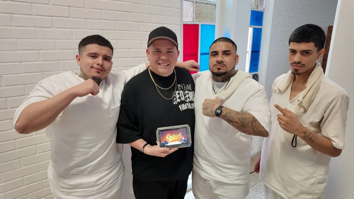 Speaker holding tablet with inmates showing Worthy People podcast