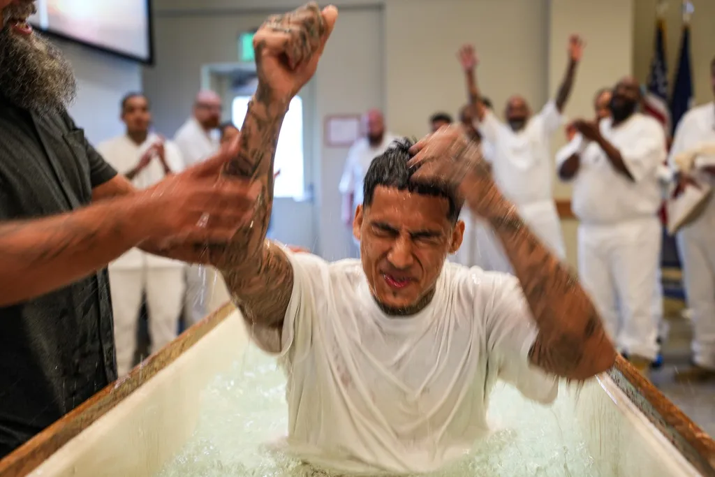 Inmate raising fist while being baptized in water