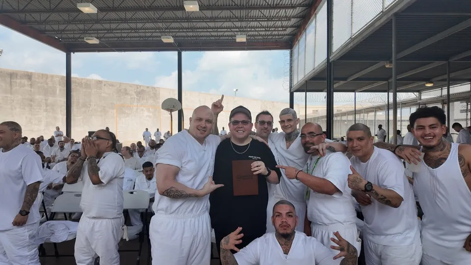 Group of inmates in white gathered in prison yard