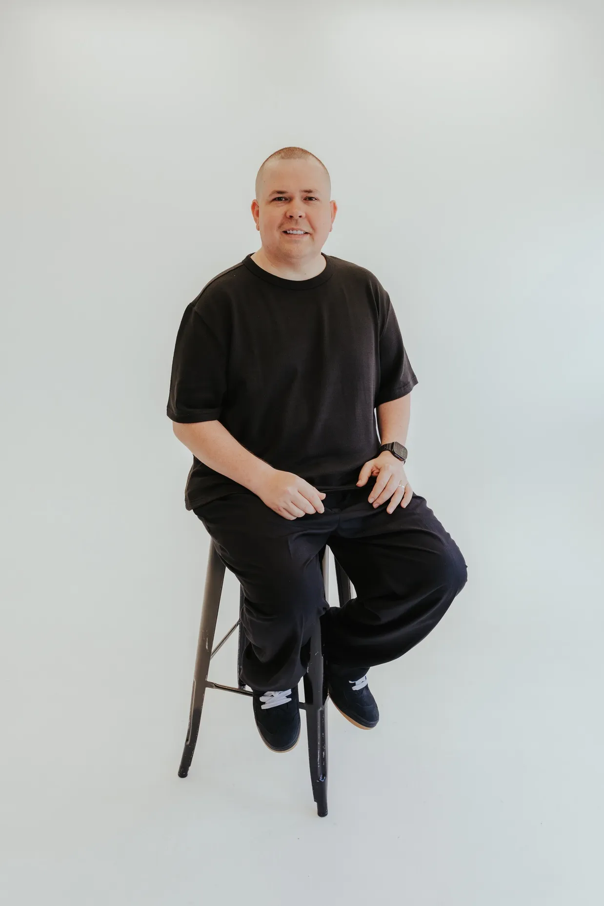 Man sitting on stool for studio portrait in black shirt