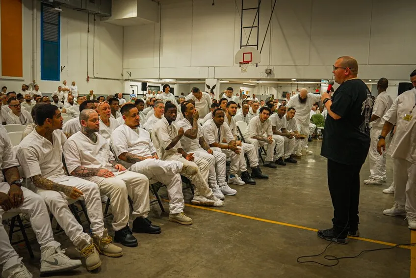 Speaker preaching to rows of inmates in prison gym