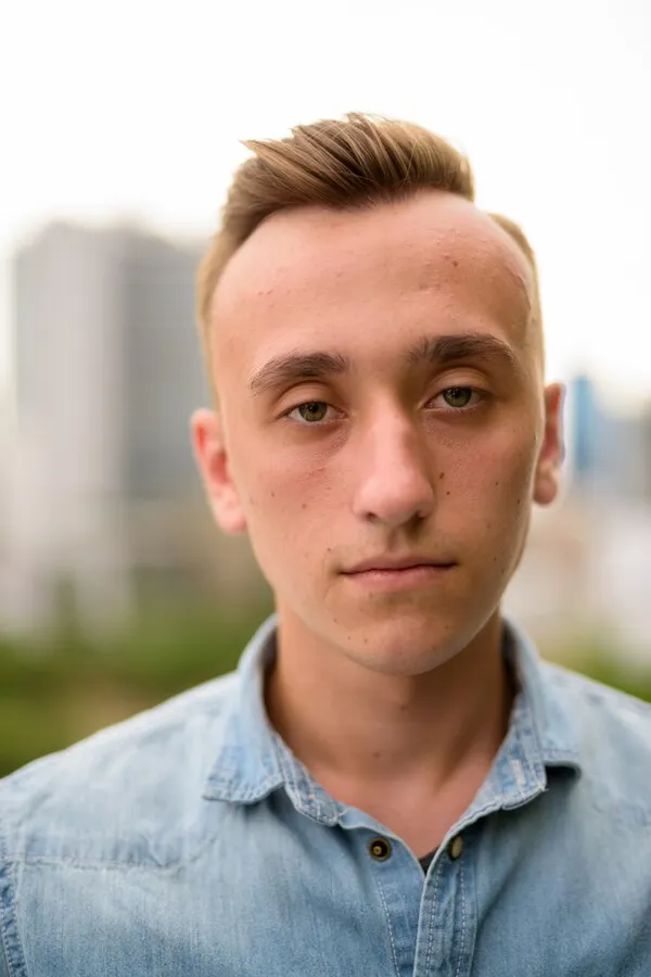 Close-up portrait of young man outdoors in denim shirt