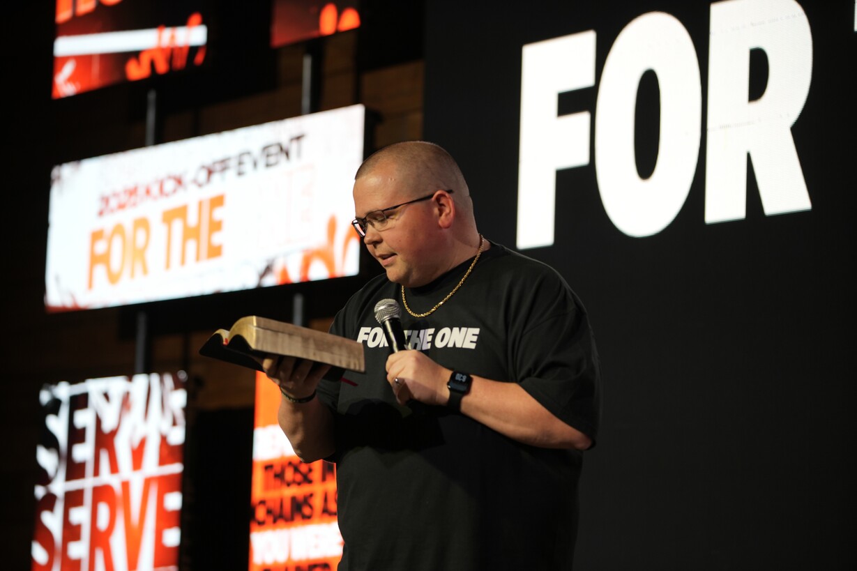 Speaker holding Bible and microphone on stage
