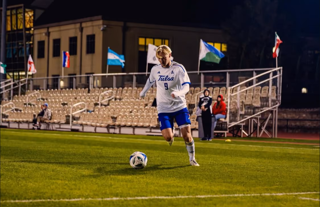 Soccer player in white Tulsa jersey with number 9 controls ball on field with empty stands behind.