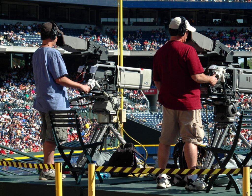 Gender inequality in sports media coverage. Two men filming a sports event.