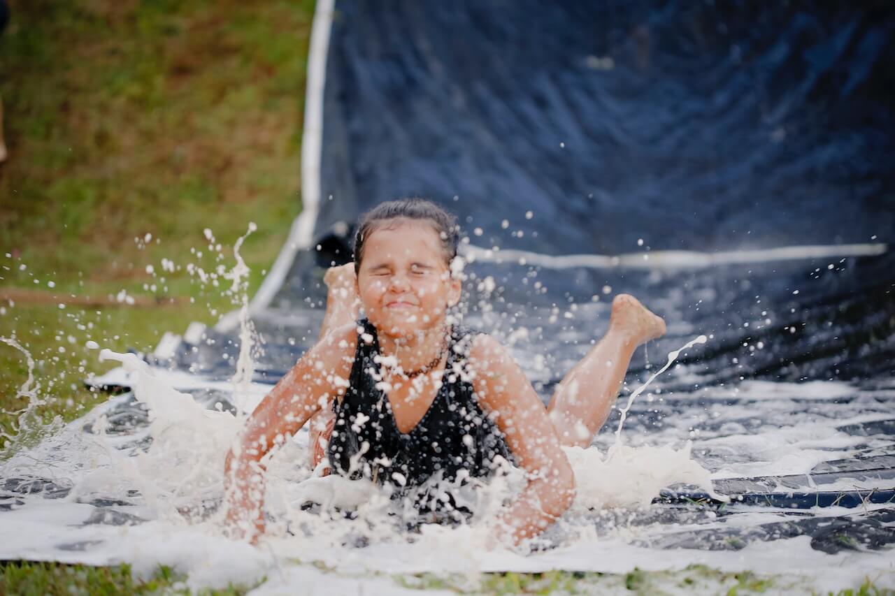Kids enjoying a slip and slide as a summer camp activity