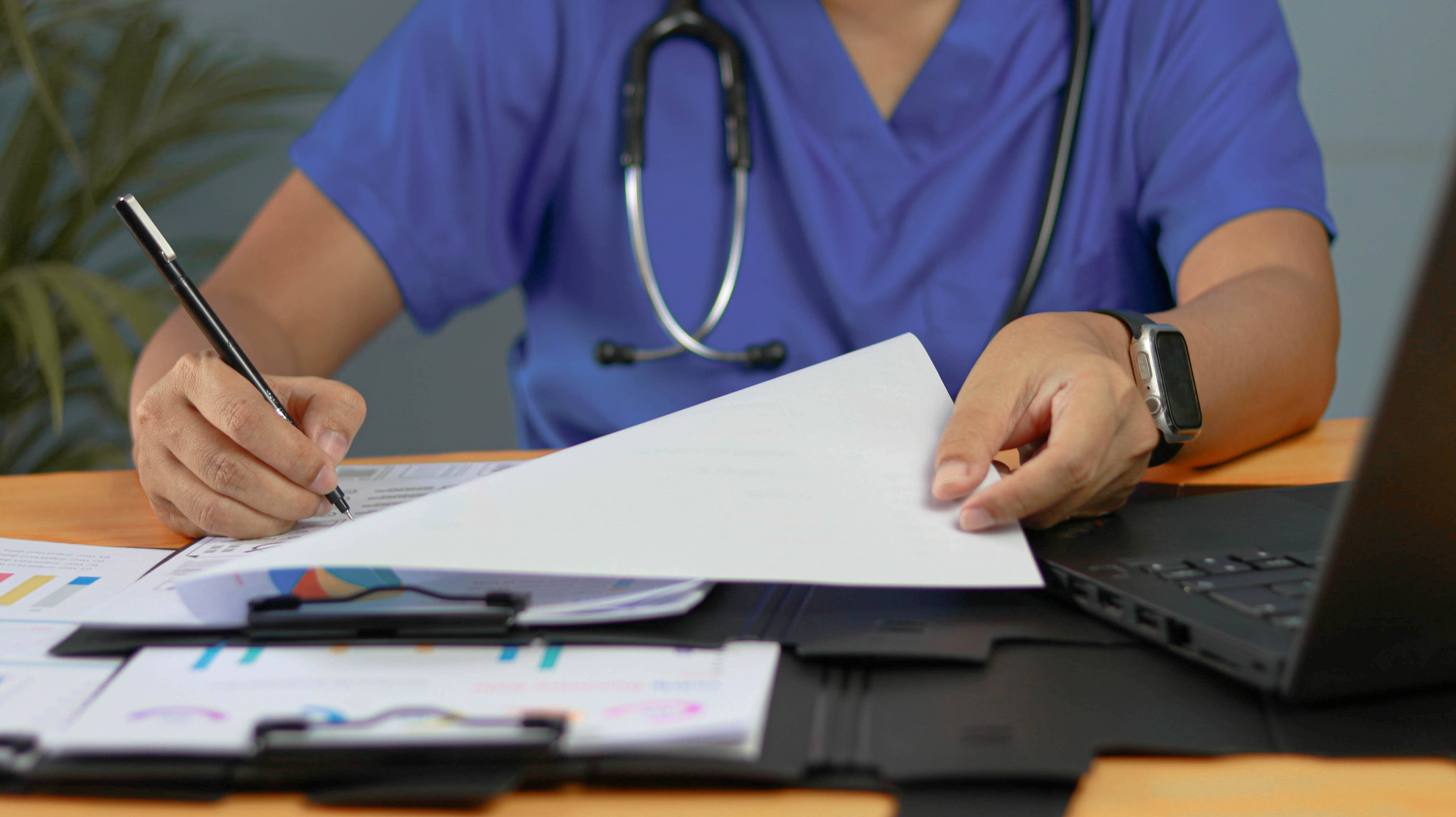 Clinician completing medical forms and documentation at a desk