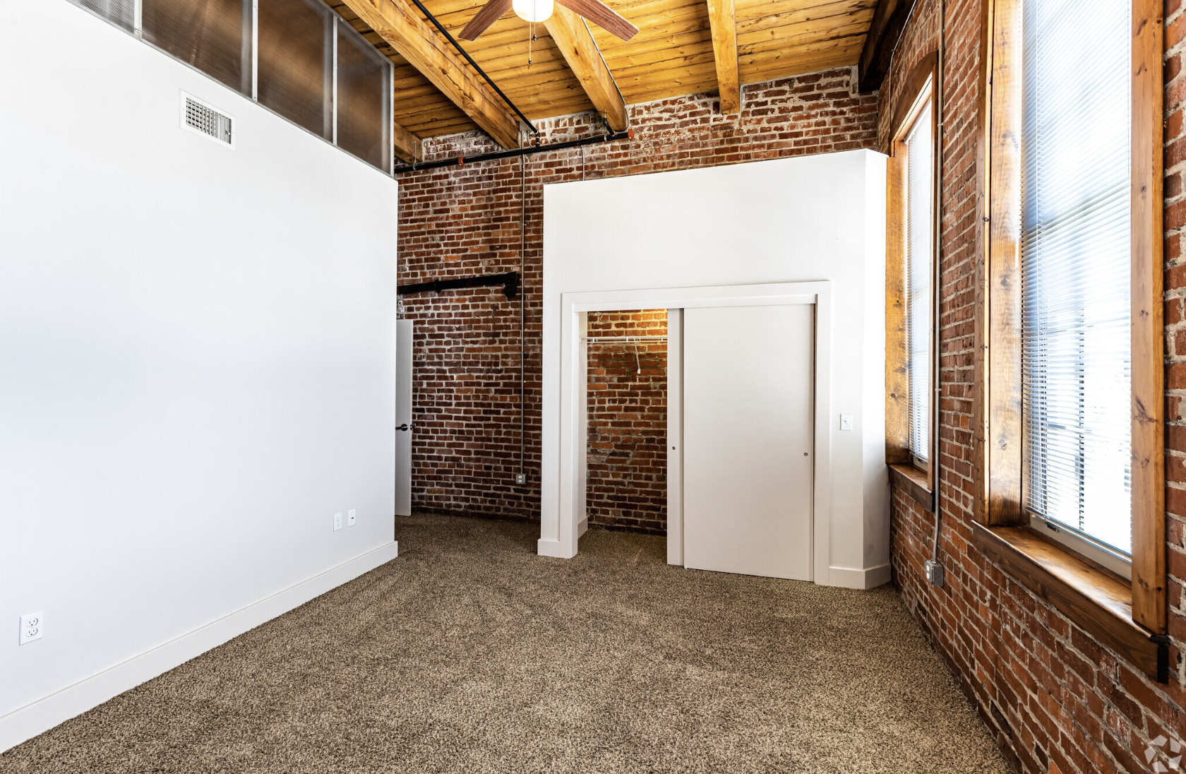 Bedroom with floor to ceiling brick walls and a closet