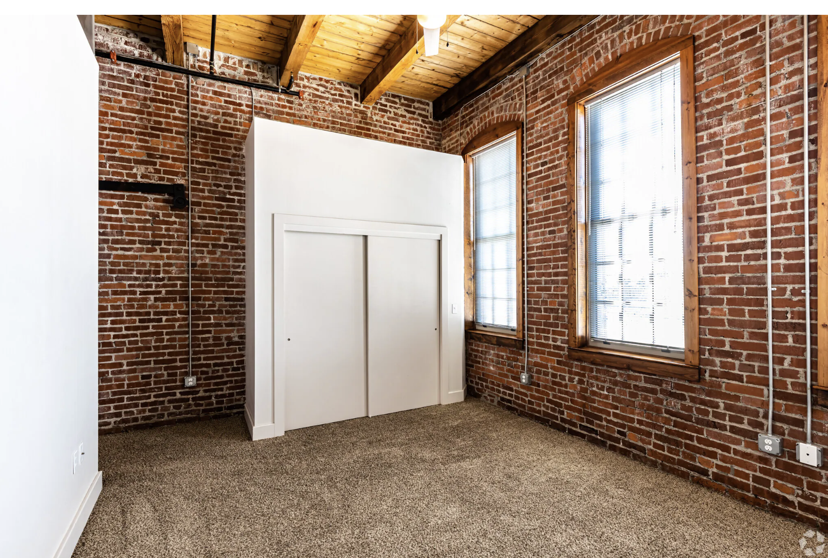 Bedroom with floor to ceiling brick walls and a closet