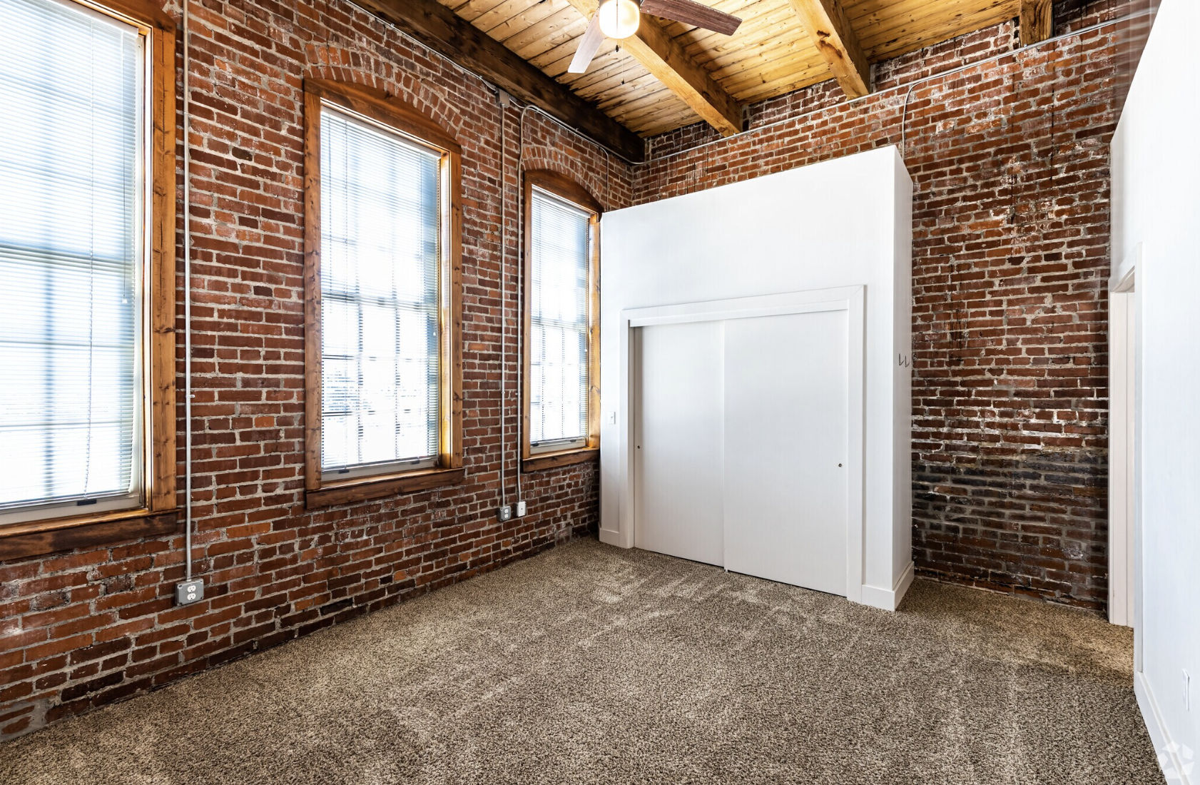 Bedroom with floor to ceiling brick walls and a closet