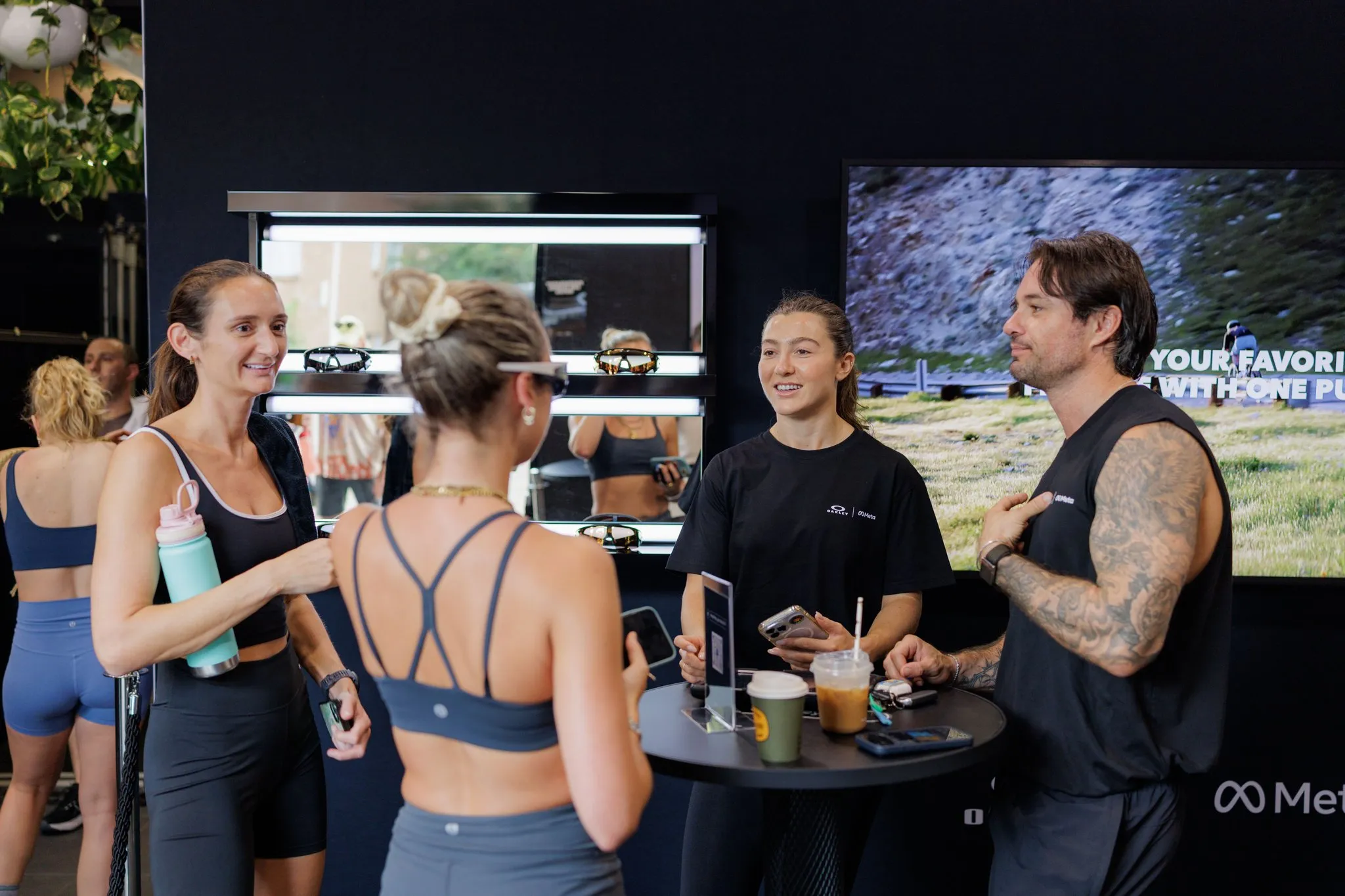 Guests talk around a table beside Meta and Oakley product displays.