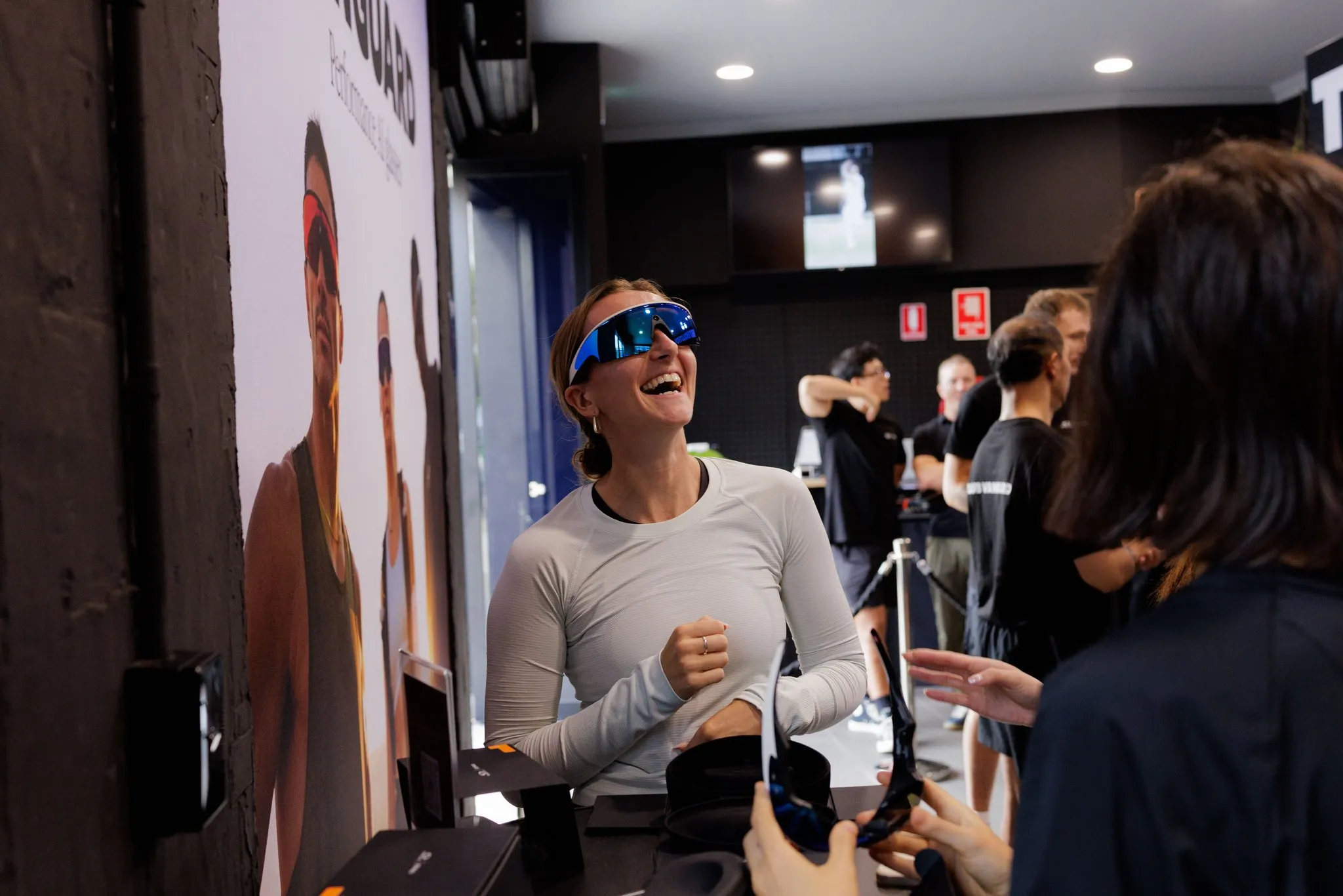 Guest wearing smart glasses talks with another attendee inside the launch venue.