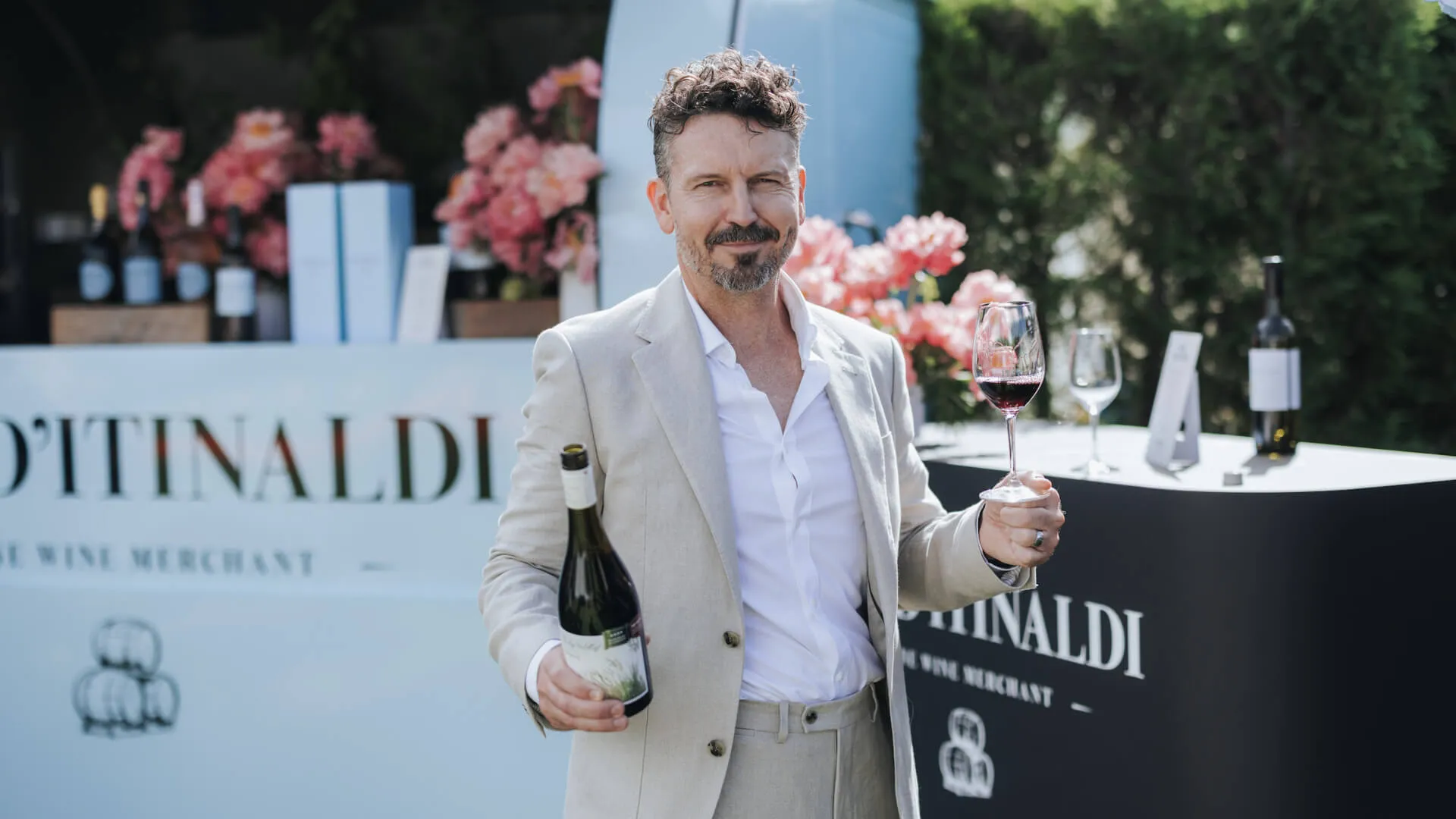 Guest holds a wine bottle and glass beside the Fin D’Itinaldi wine activation.