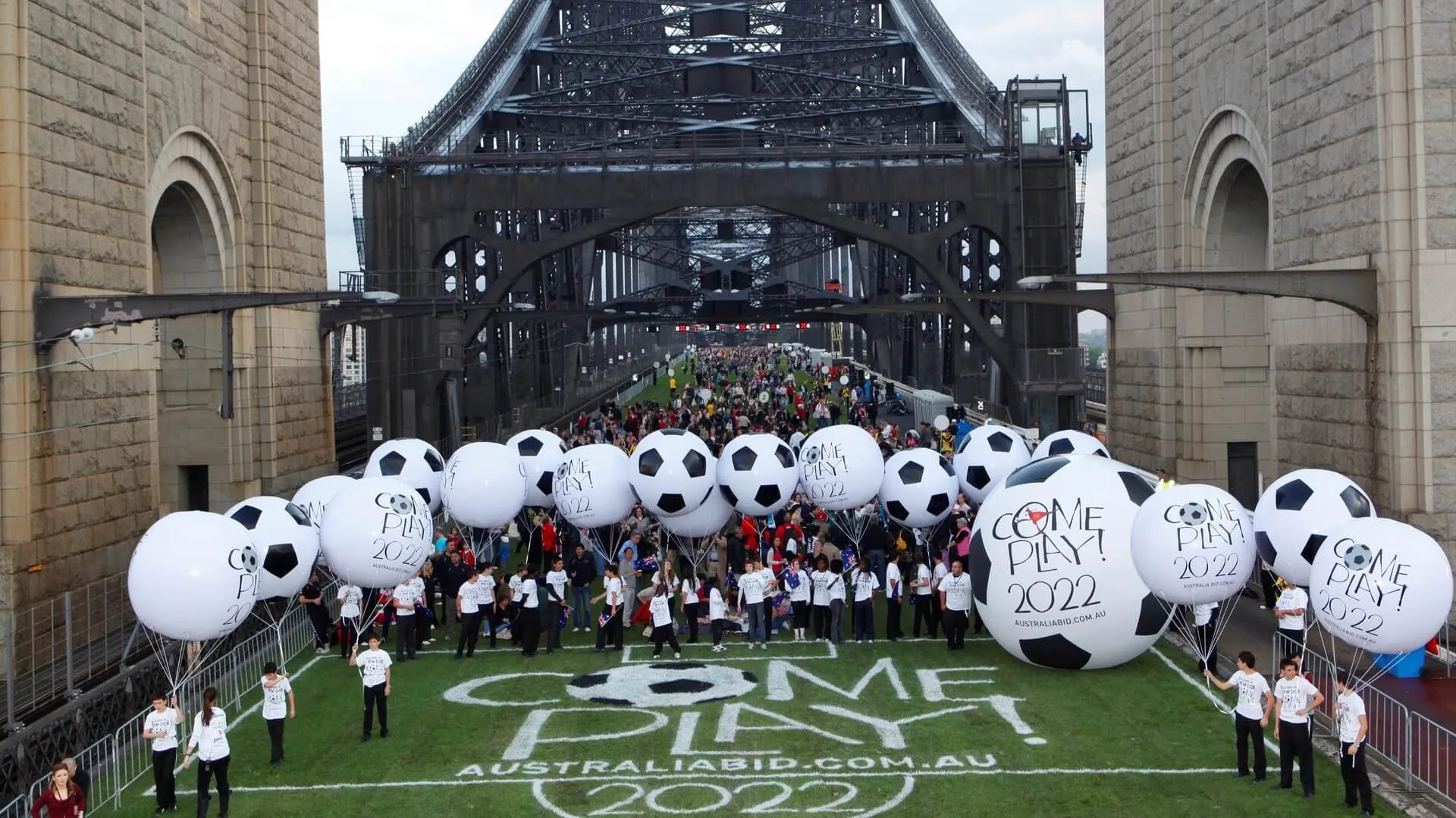 Oversized football balloons and participants fill the grass-covered bridge roadway.