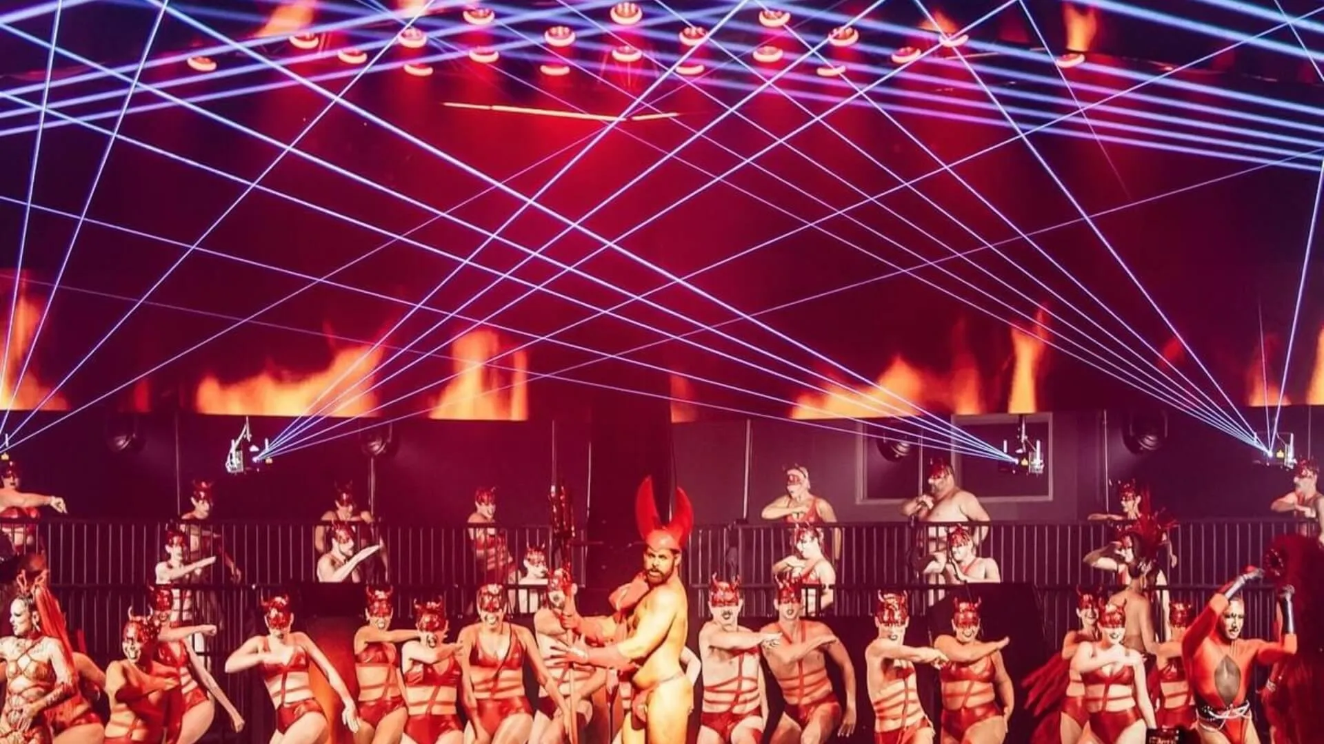 Dancers perform beneath a web of laser beams at a Mardi Gras event.