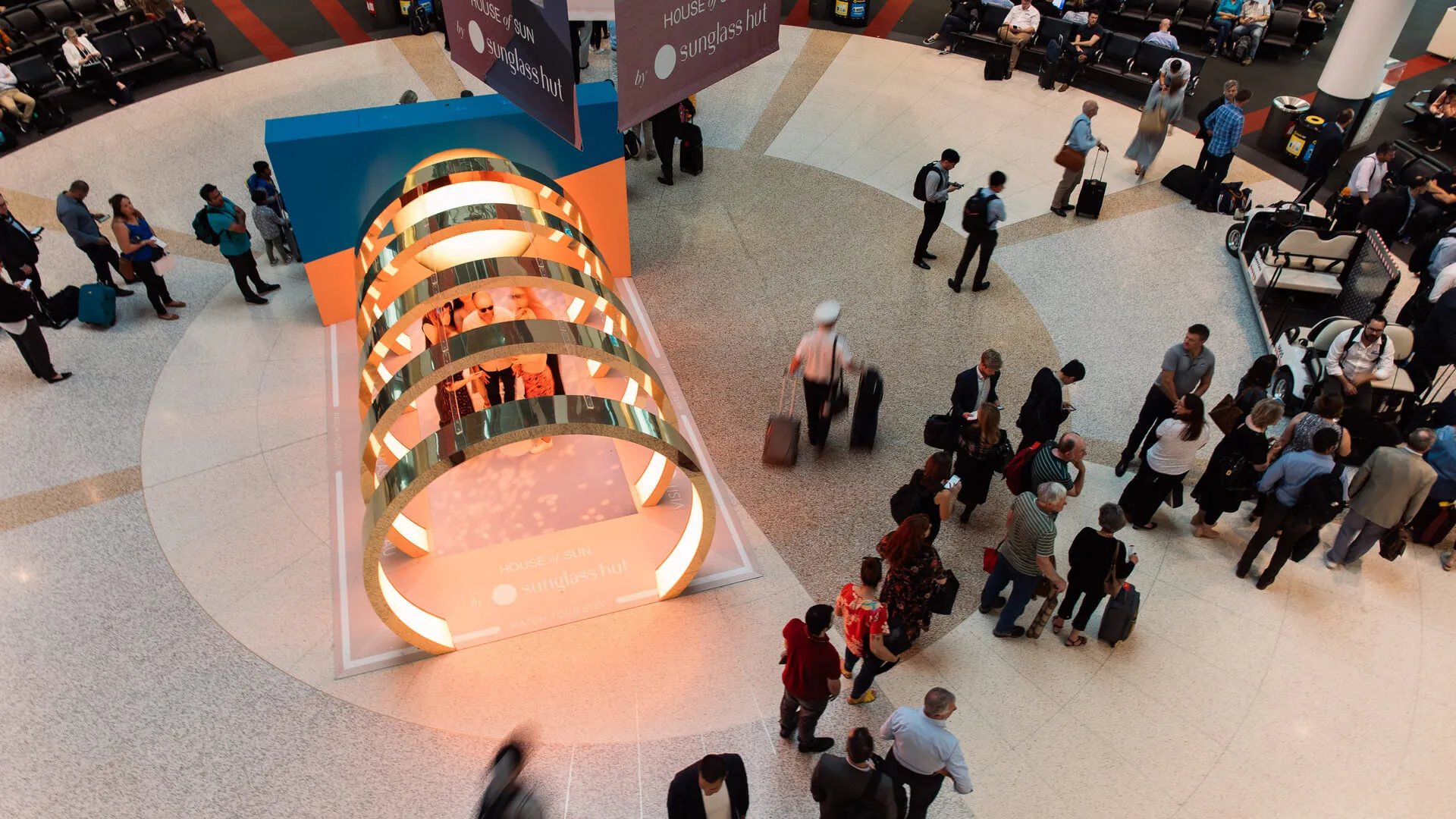 Visitors gather around a tunnel of illuminated arches in a shopping centre.
