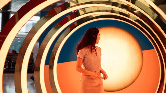 Guest stands inside a gold-and-orange arch at the House of Sun activation.