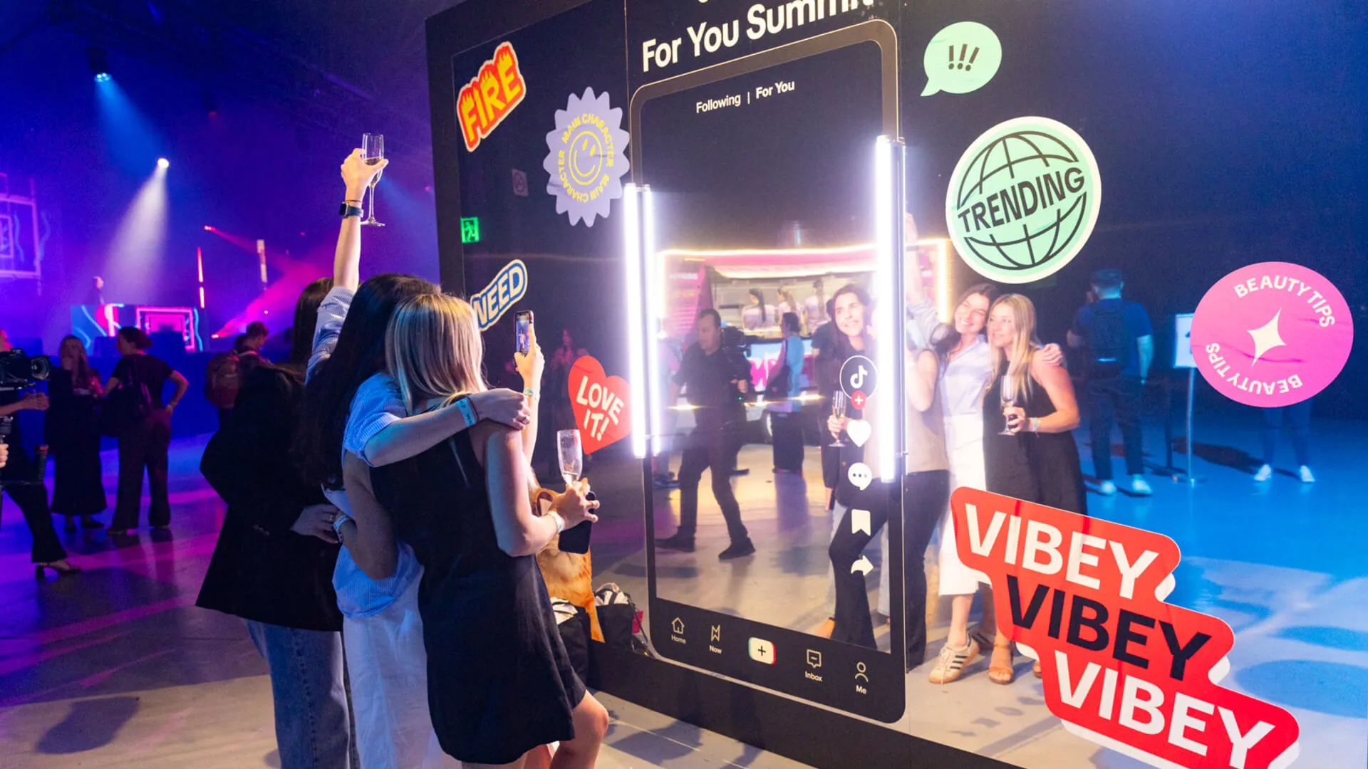 Guests pose beside a giant phone-shaped photo installation at the TikTok summit.