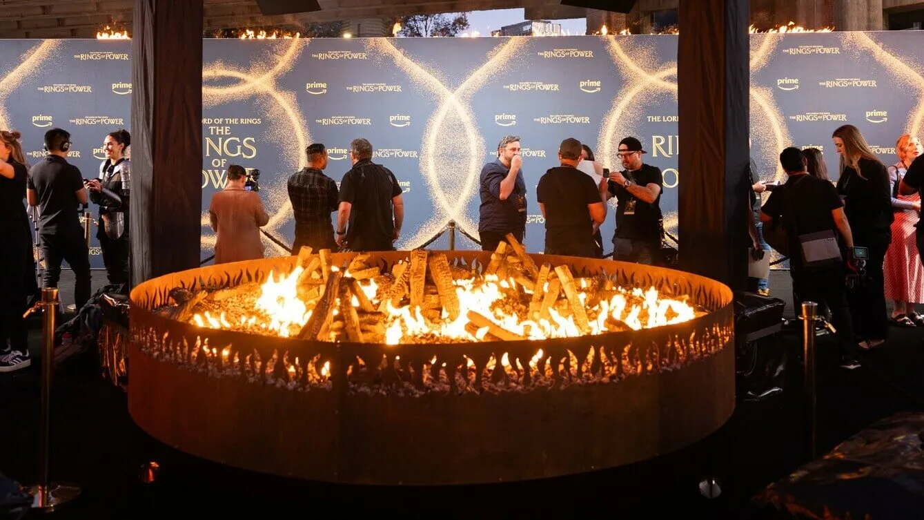Guests gather around a circular fire installation at the Rings of Power premiere.