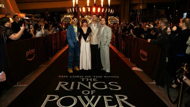 Guests pose on the Rings of Power premiere carpet surrounded by photographers.