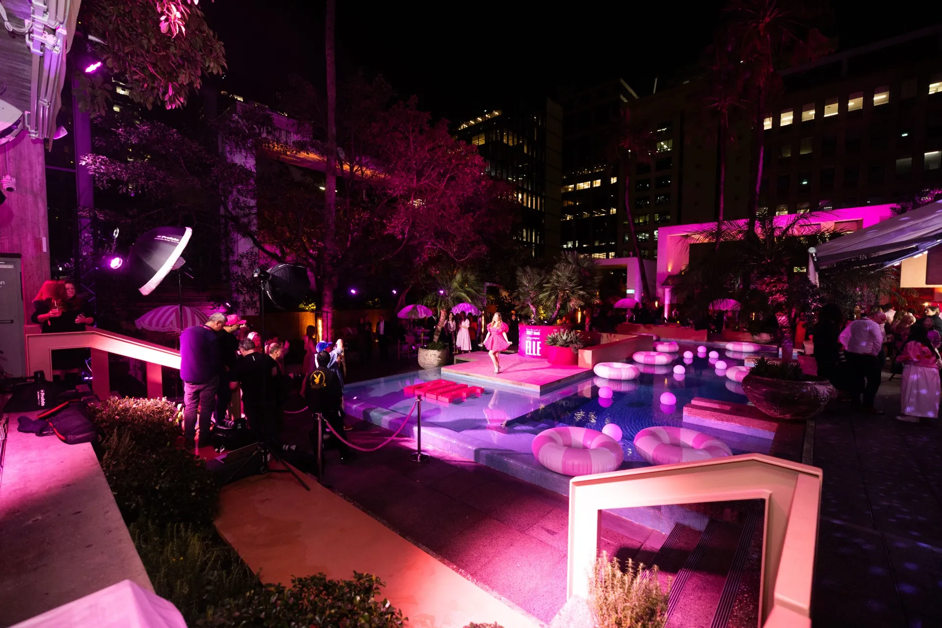Guests gather around a pool illuminated with pink lighting at the Elle launch.