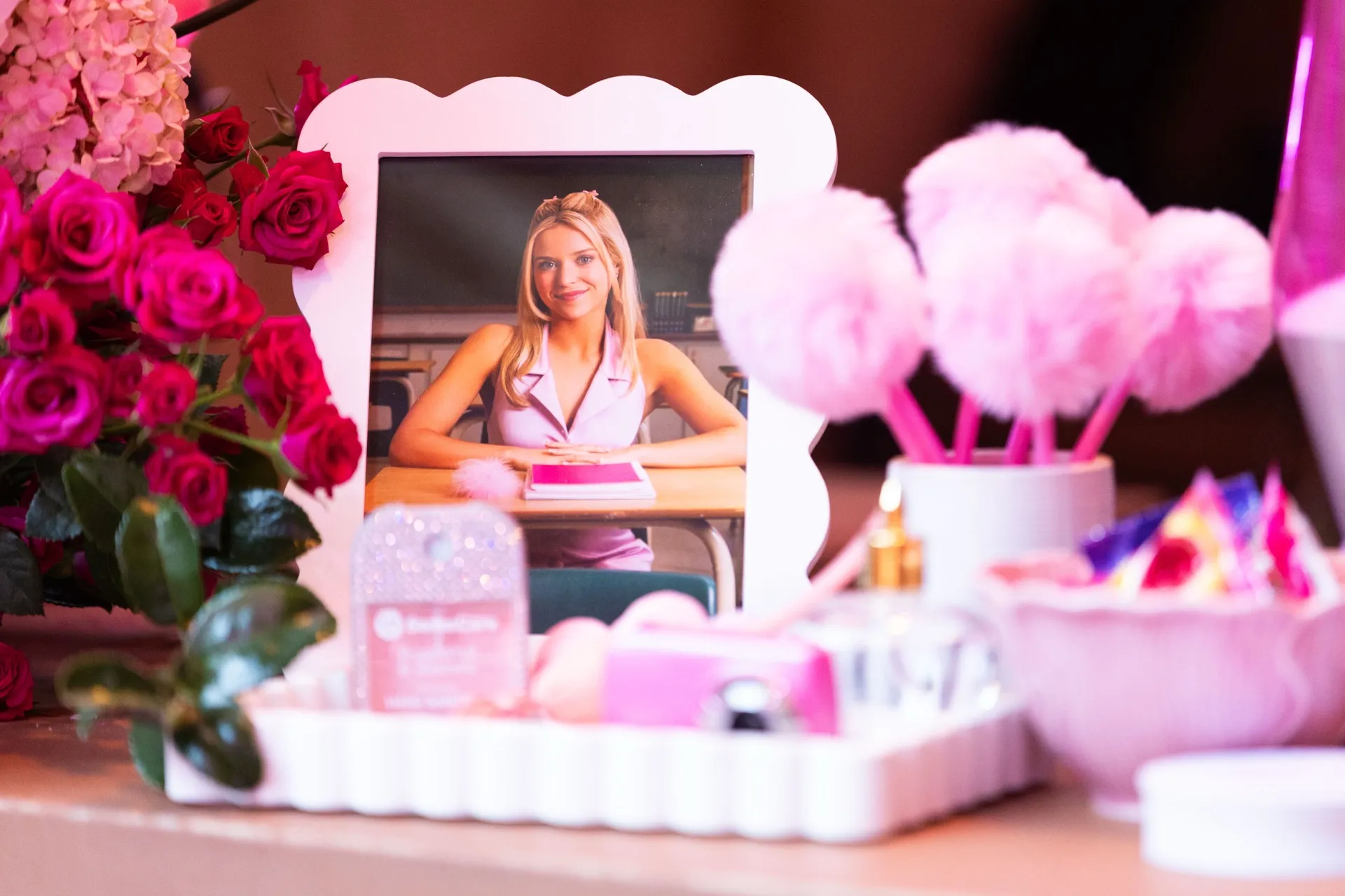Guest is reflected in a vanity mirror surrounded by pink flowers and beauty products.