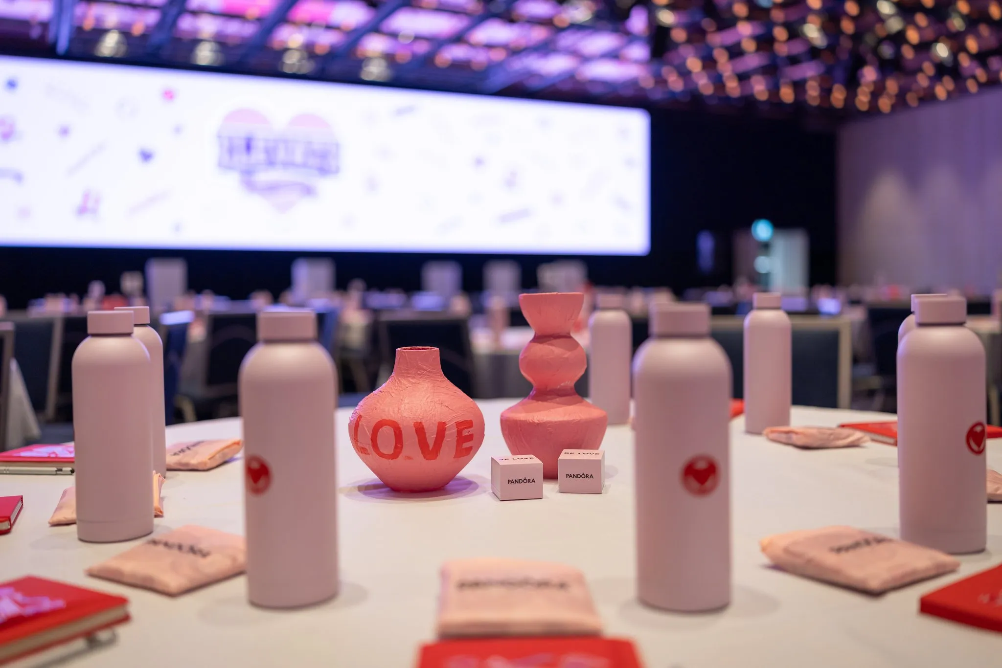 Pandora conference table with pink bottles, flowers and a vase marked LOVE.