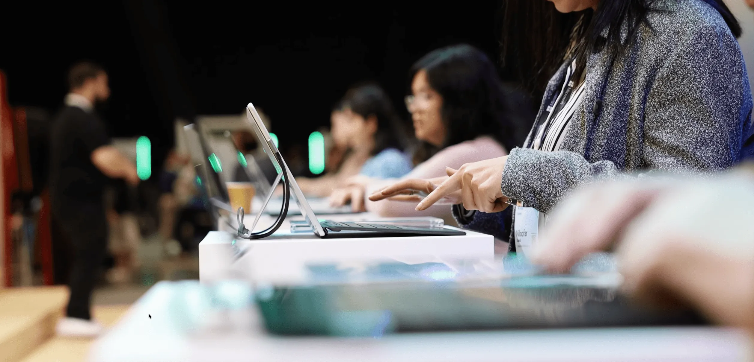 Attendees use Surface devices arranged along a demonstration table.