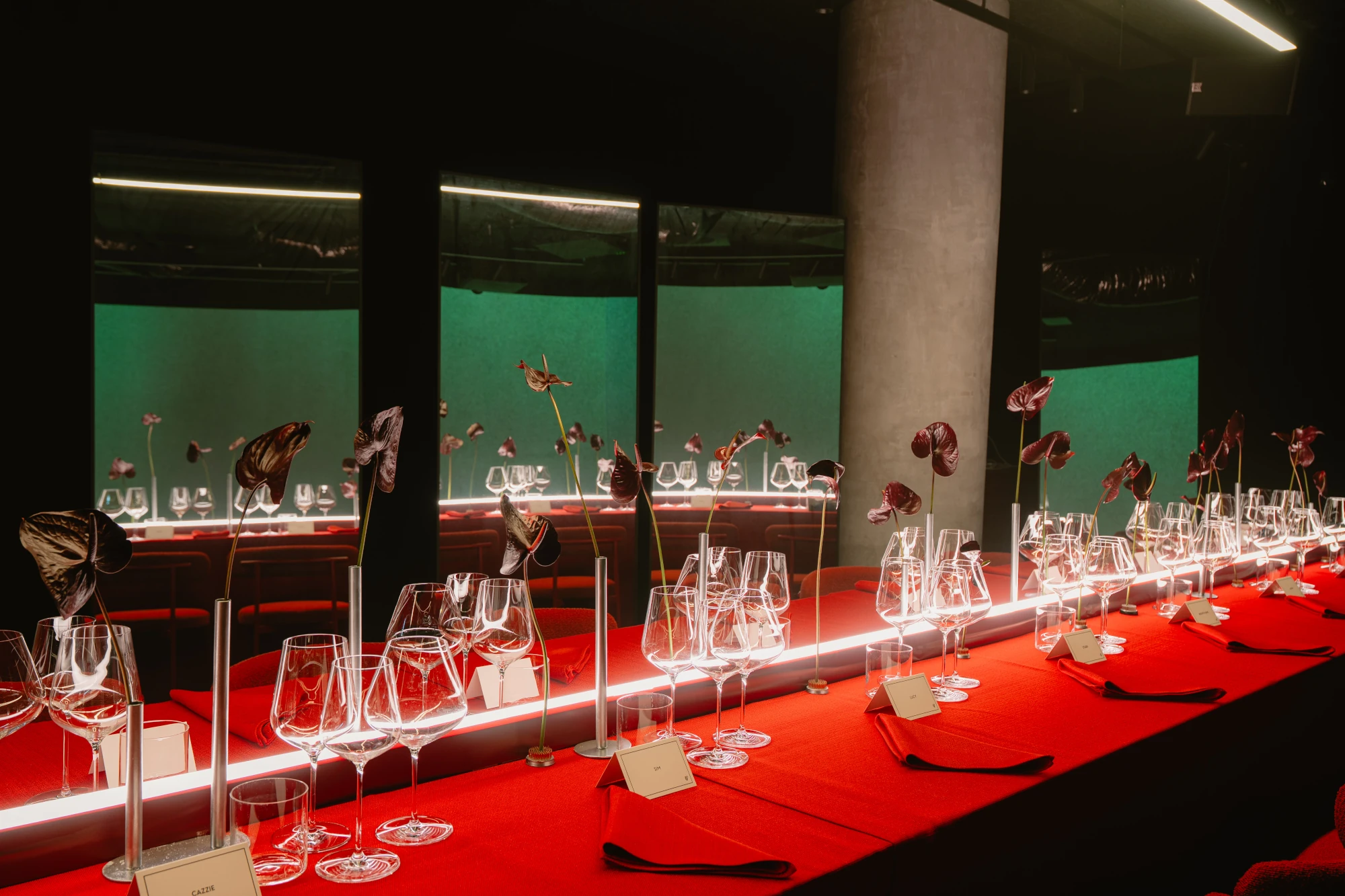 Long red dining table with glassware and hanging flowers at the Verity event.