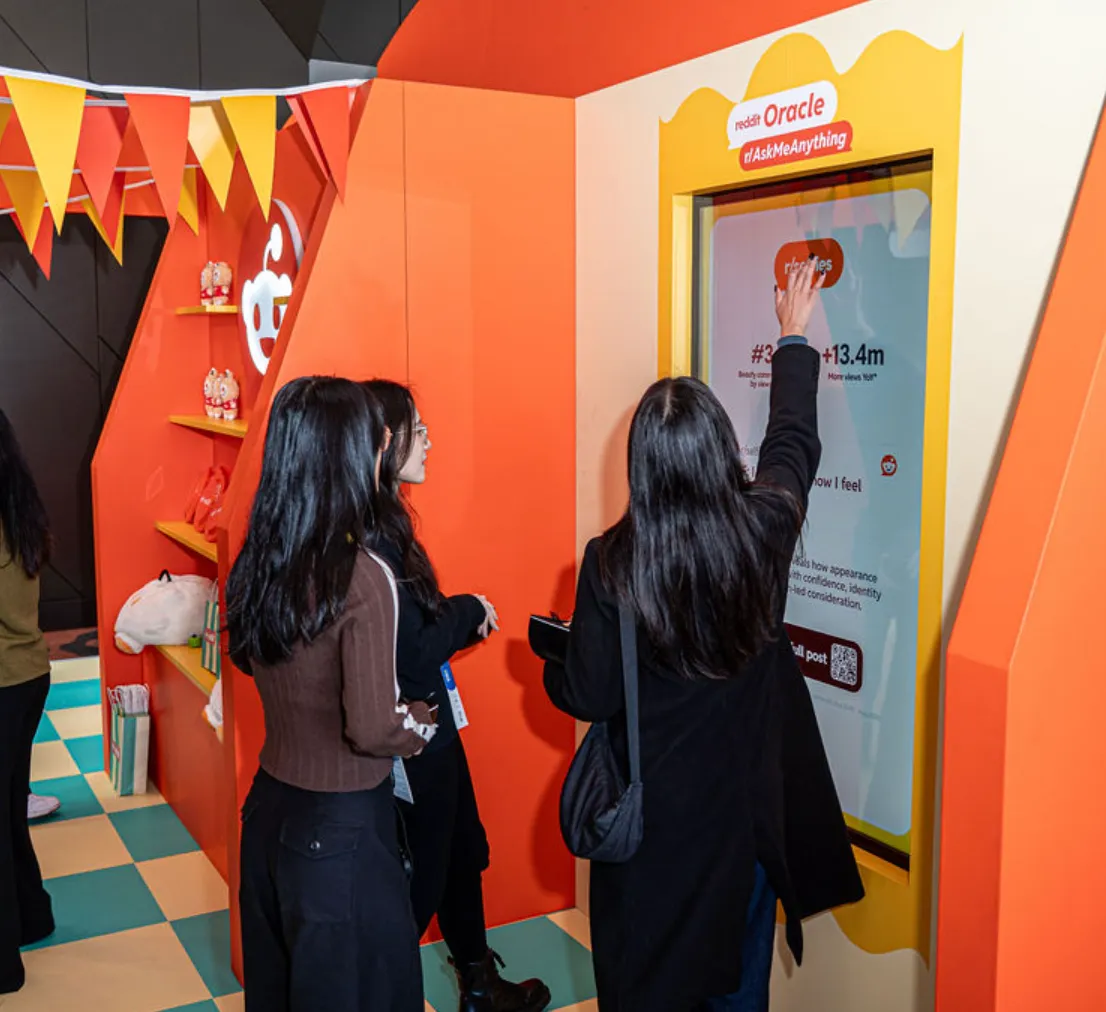 Visitors explore an orange-and-yellow interactive Reddit display.