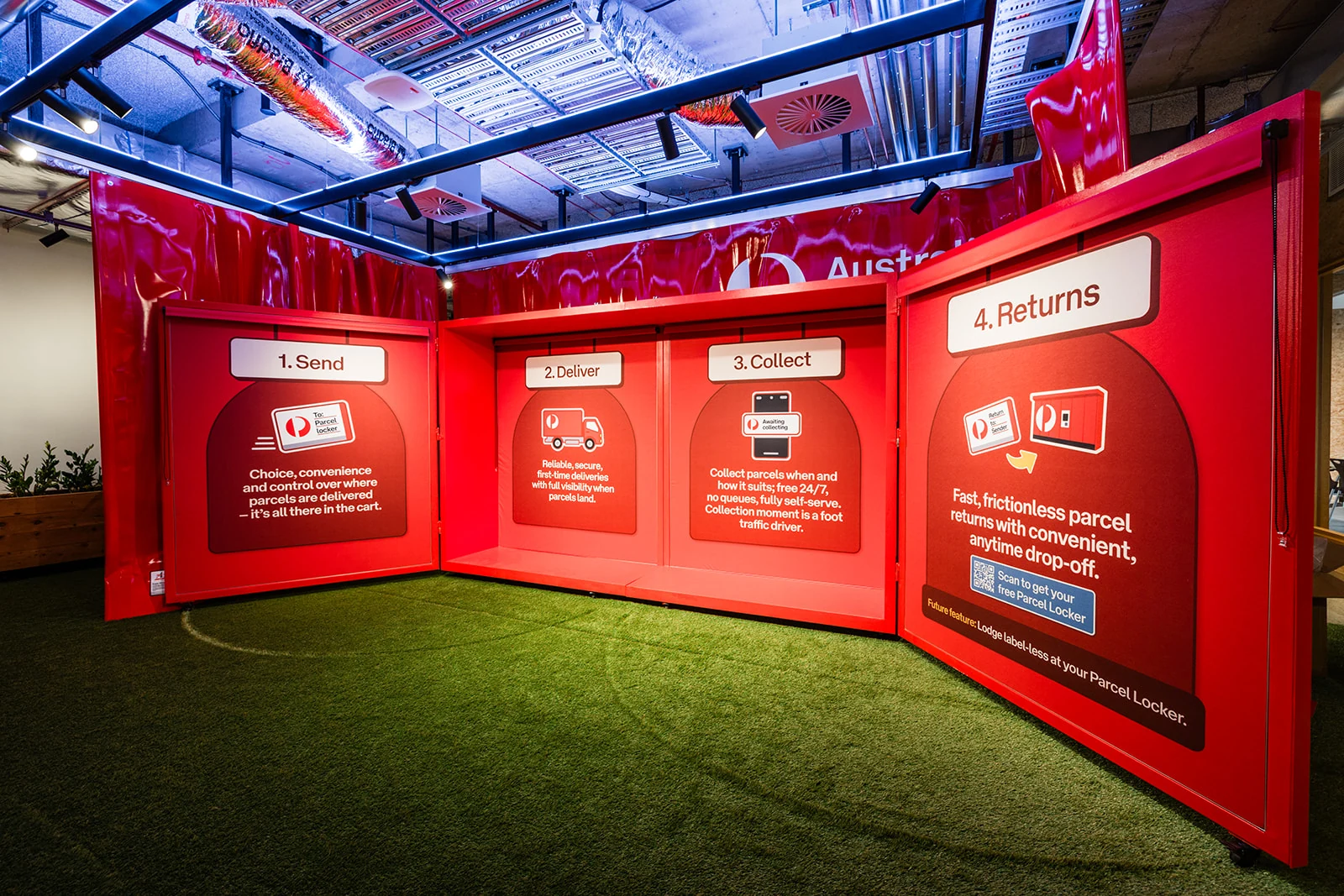 Red instructional panels surround artificial grass in the Australia Post Locker Land installation.