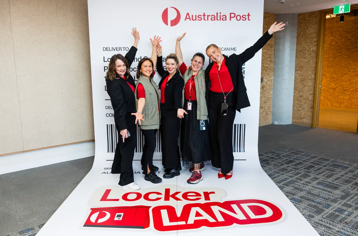 Five guests raise their arms at the Australia Post Locker Land photo backdrop.