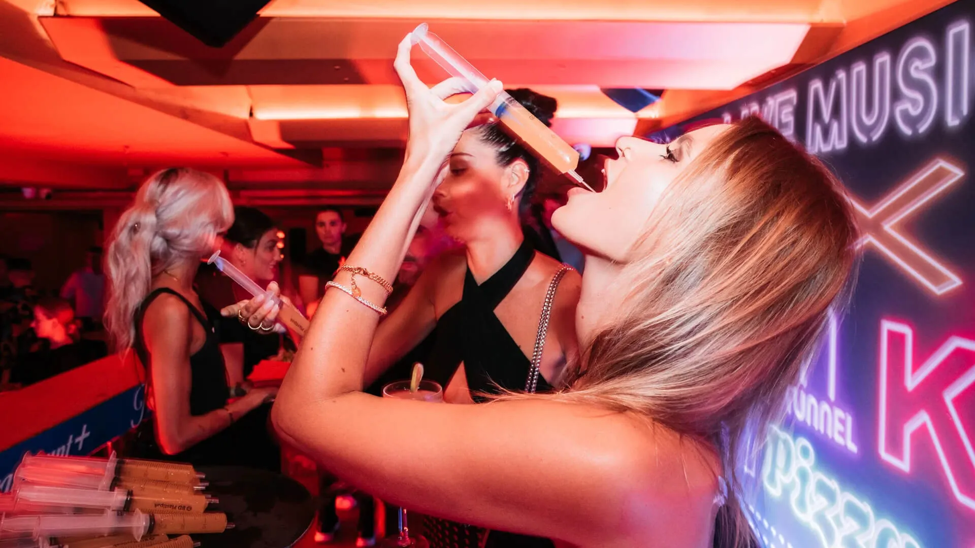 Guest drinks from a bottle beneath red lighting at the Last King of the Cross launch.