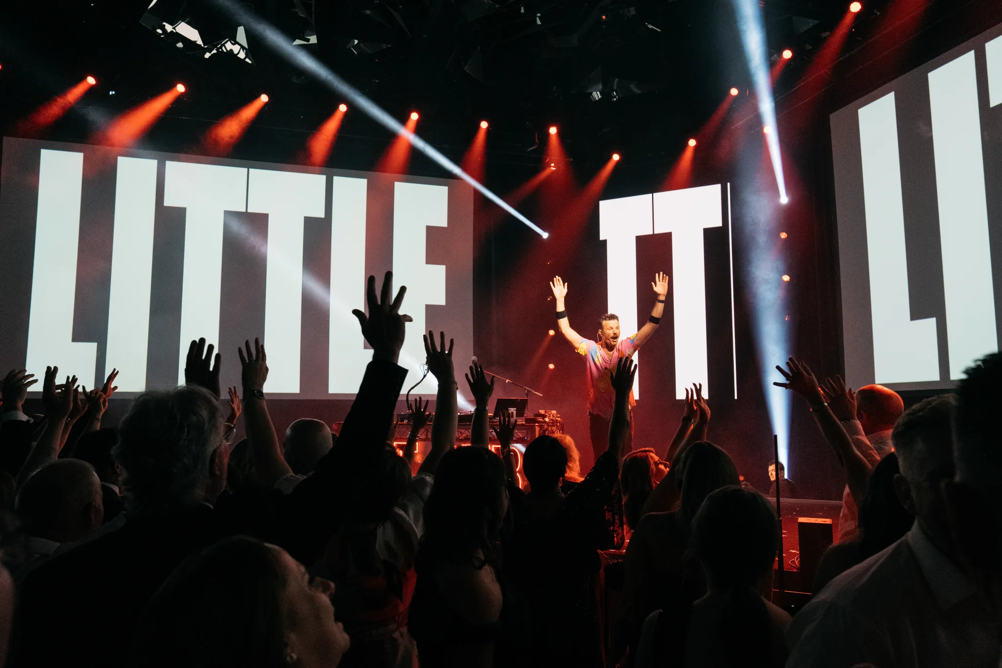 A live performer under red lights with guests raising their hands in front of the Toyota awards stage.