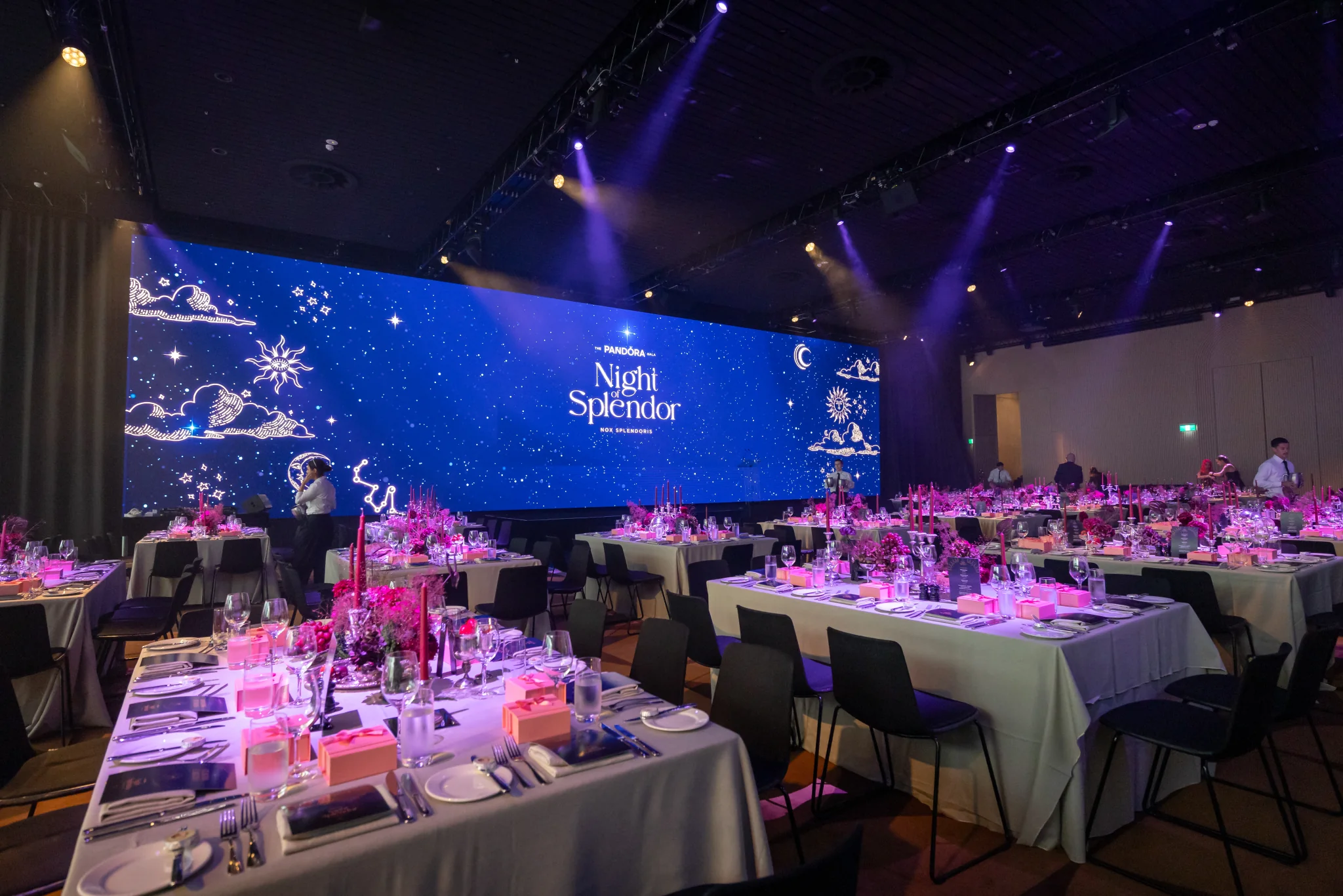 Pandora gala tables beneath a blue Night of Splendor stage screen and purple spotlights.