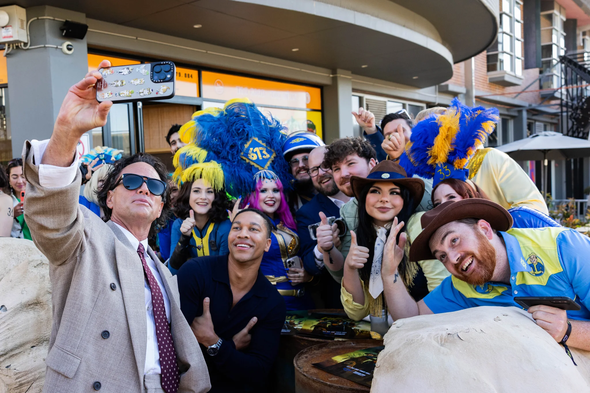 Cast members take a selfie with costumed fans at the outdoor Fallout premiere activation.