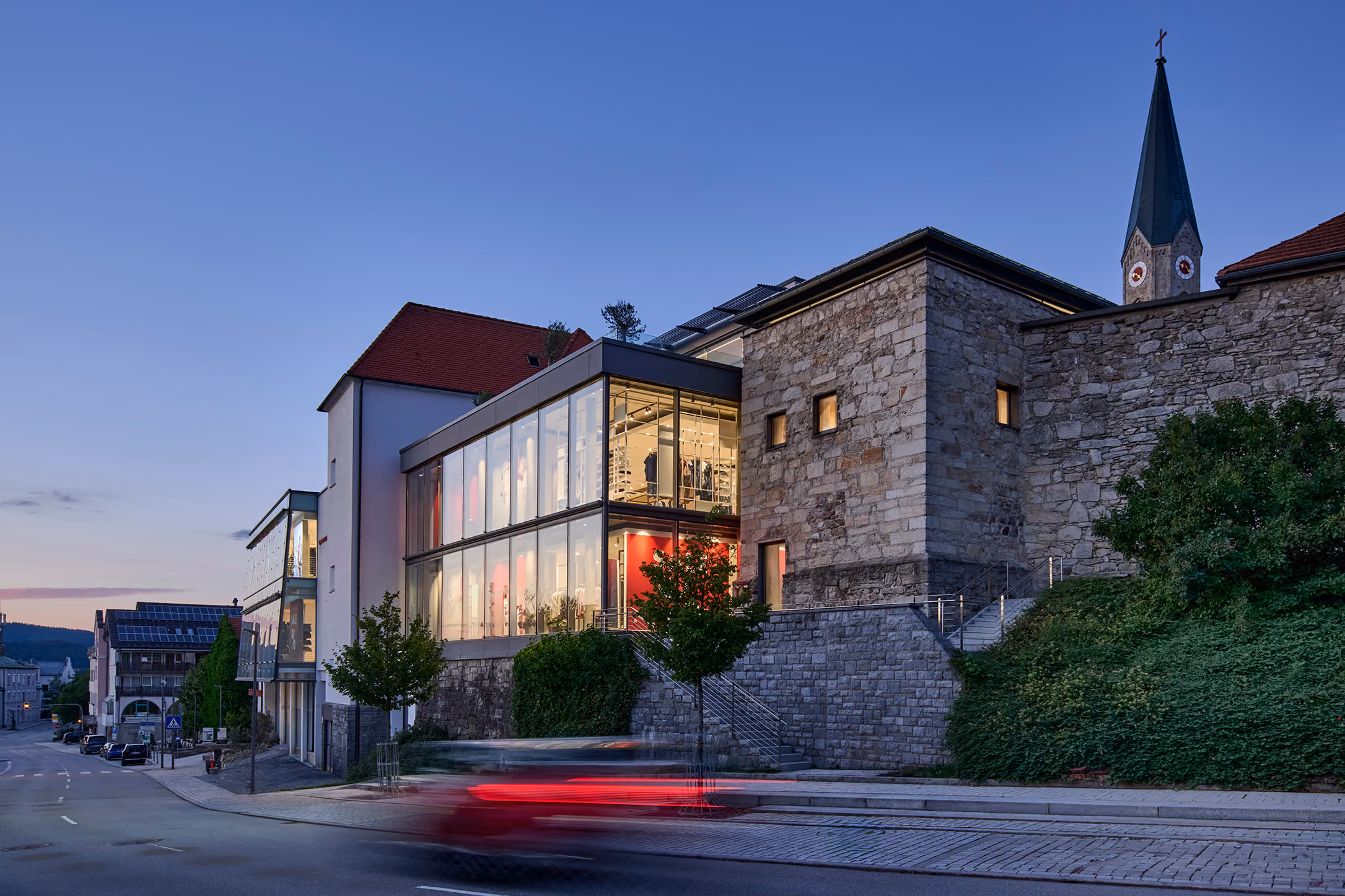 Modehaus GARHAMMER in Waldkirchen am Abend mit Kirchturm im Hintergrund