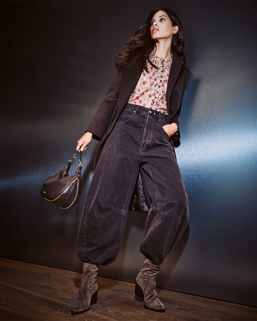 Model in dunklem Blazer, Ballonhose und Stiefeln mit brauner Tasche