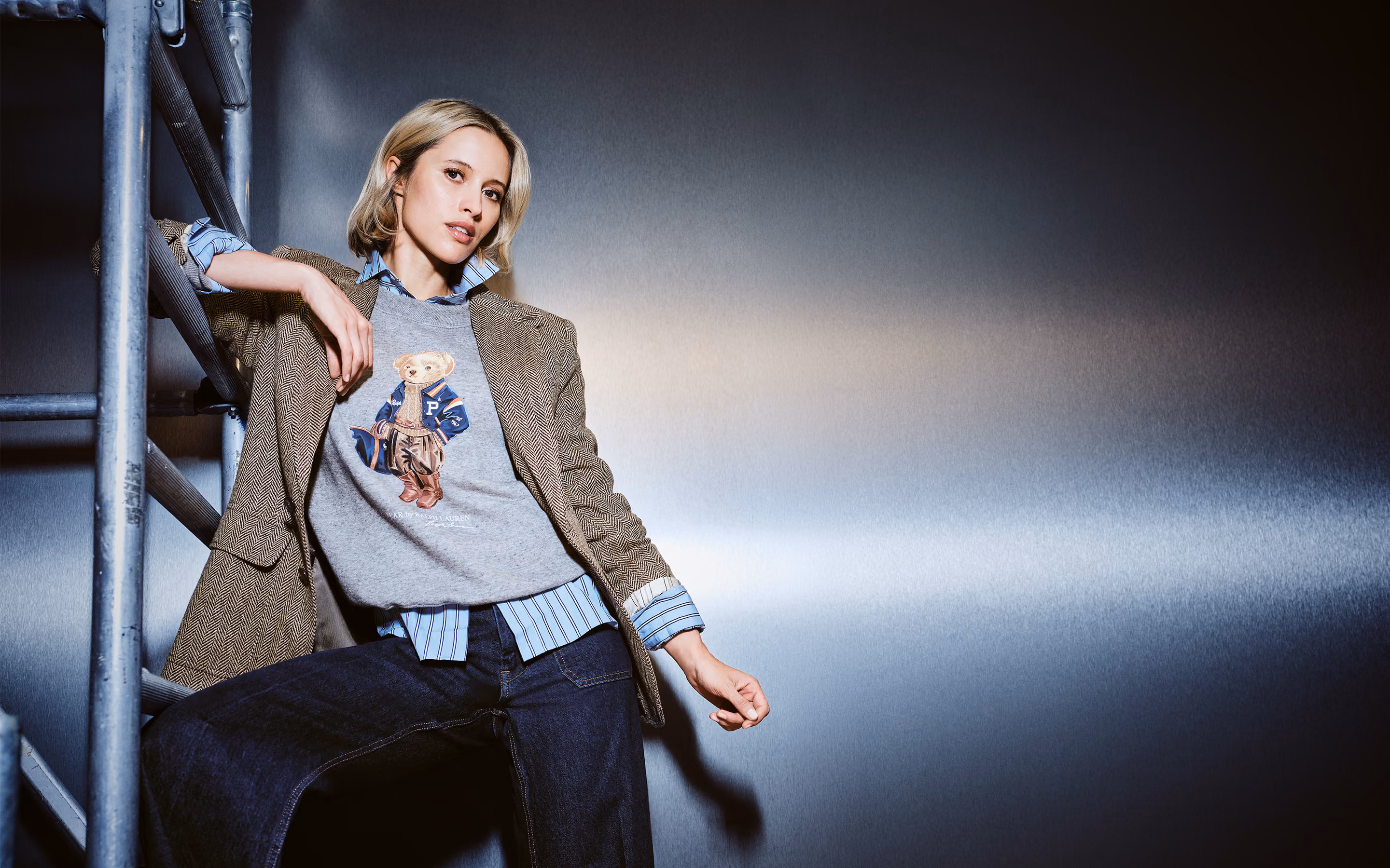 Model in Tweed-Blazer und Pullover mit Teddy-Motiv an einem Gerüst – Damenmode bei GARHAMMER