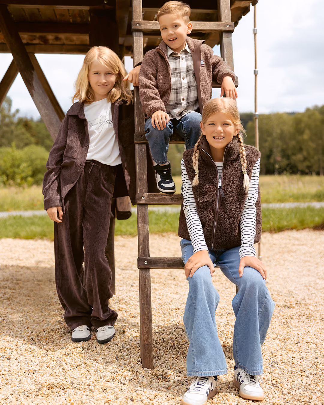 Drei Kinder in Herbstmode an einem Klettergerüst