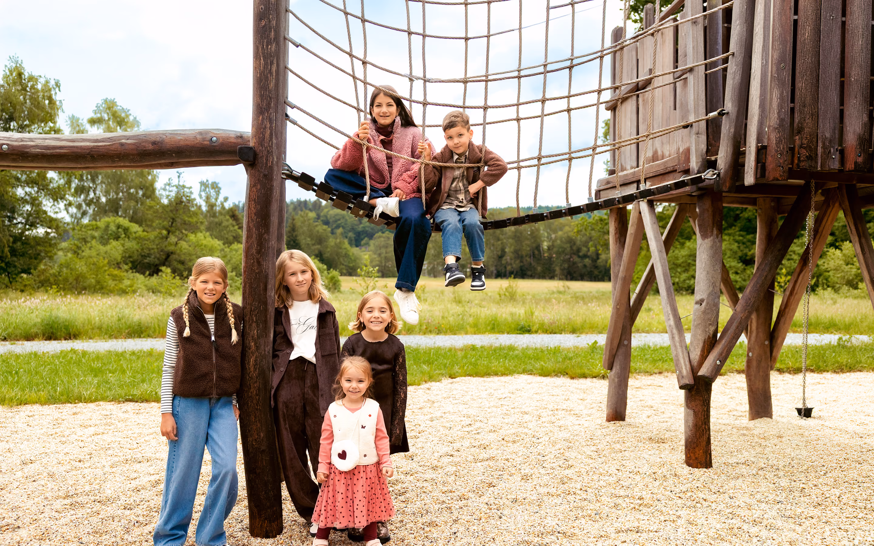 Kinder in Herbstmode auf einem Holzspielplatz – Kindermode bei GARHAMMER