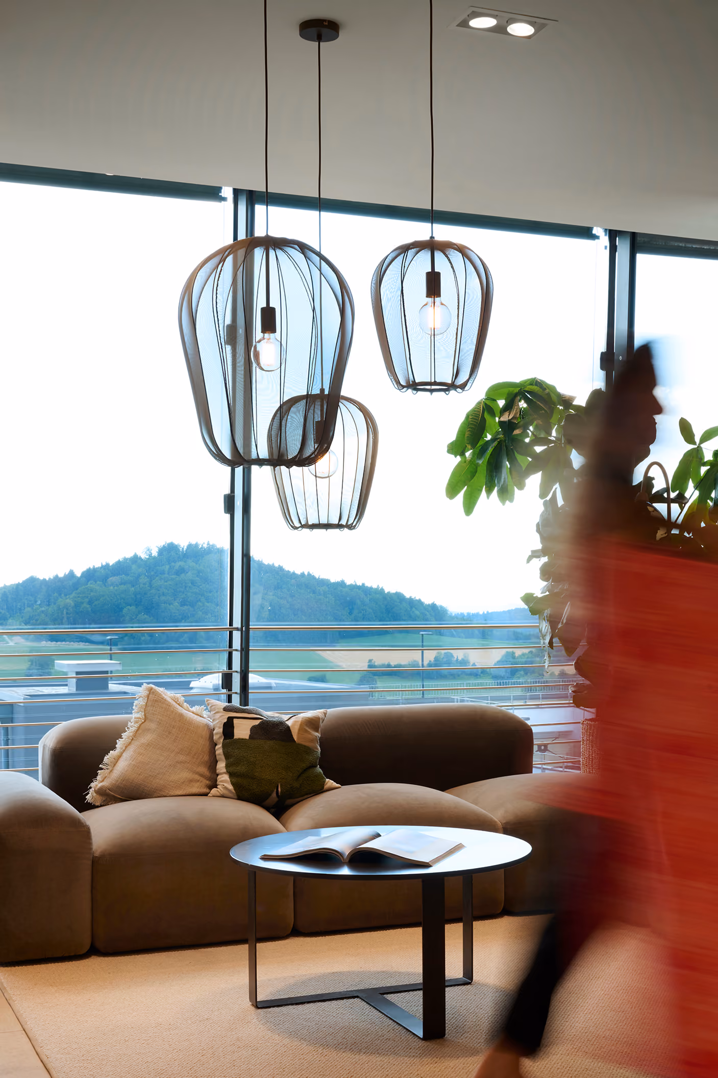 Lounge mit Sofa, Glasleuchten und Blick ins Grüne bei GARHAMMER