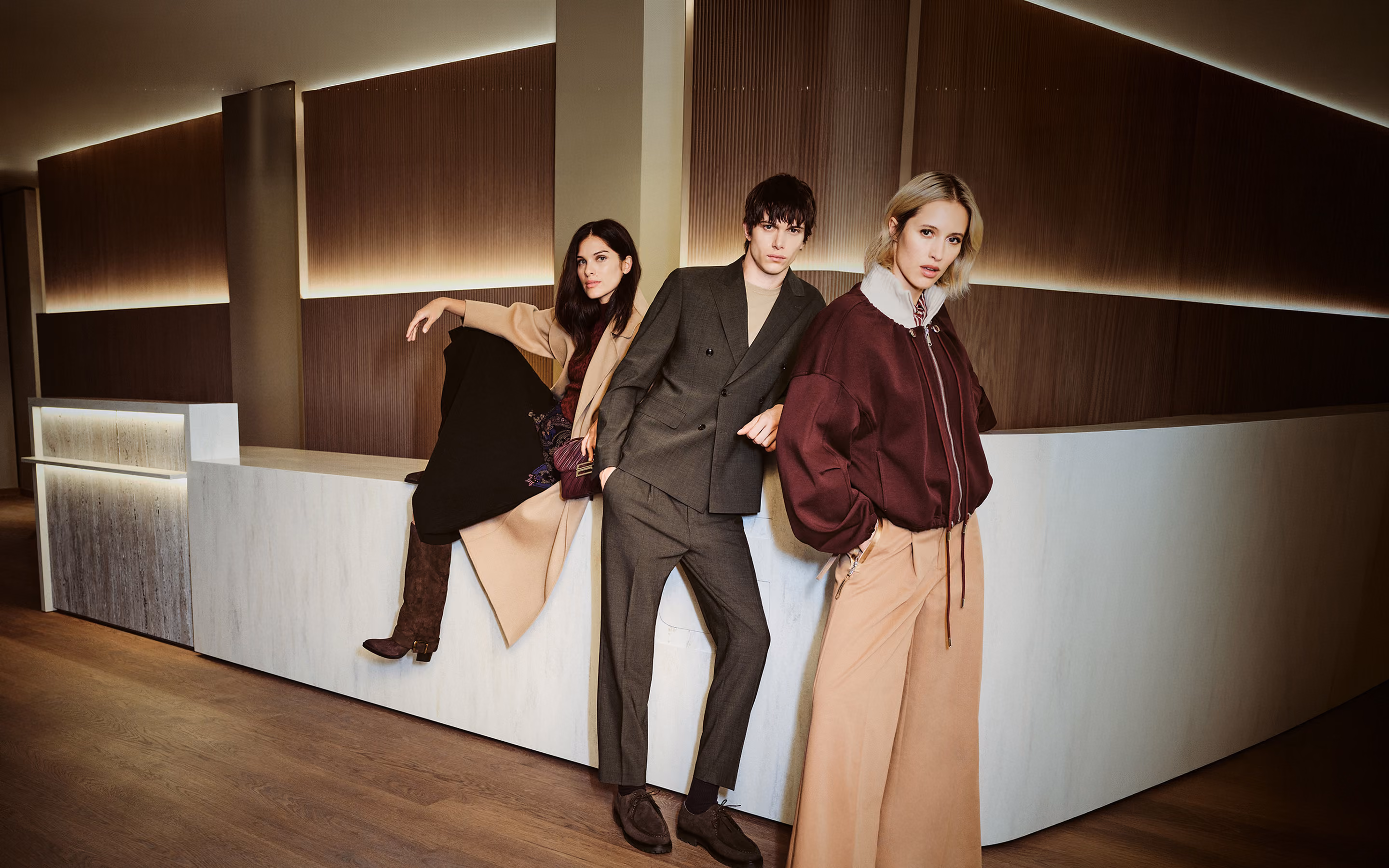 Drei Models in Herbstmode an einer beleuchteten Theke bei GARHAMMER