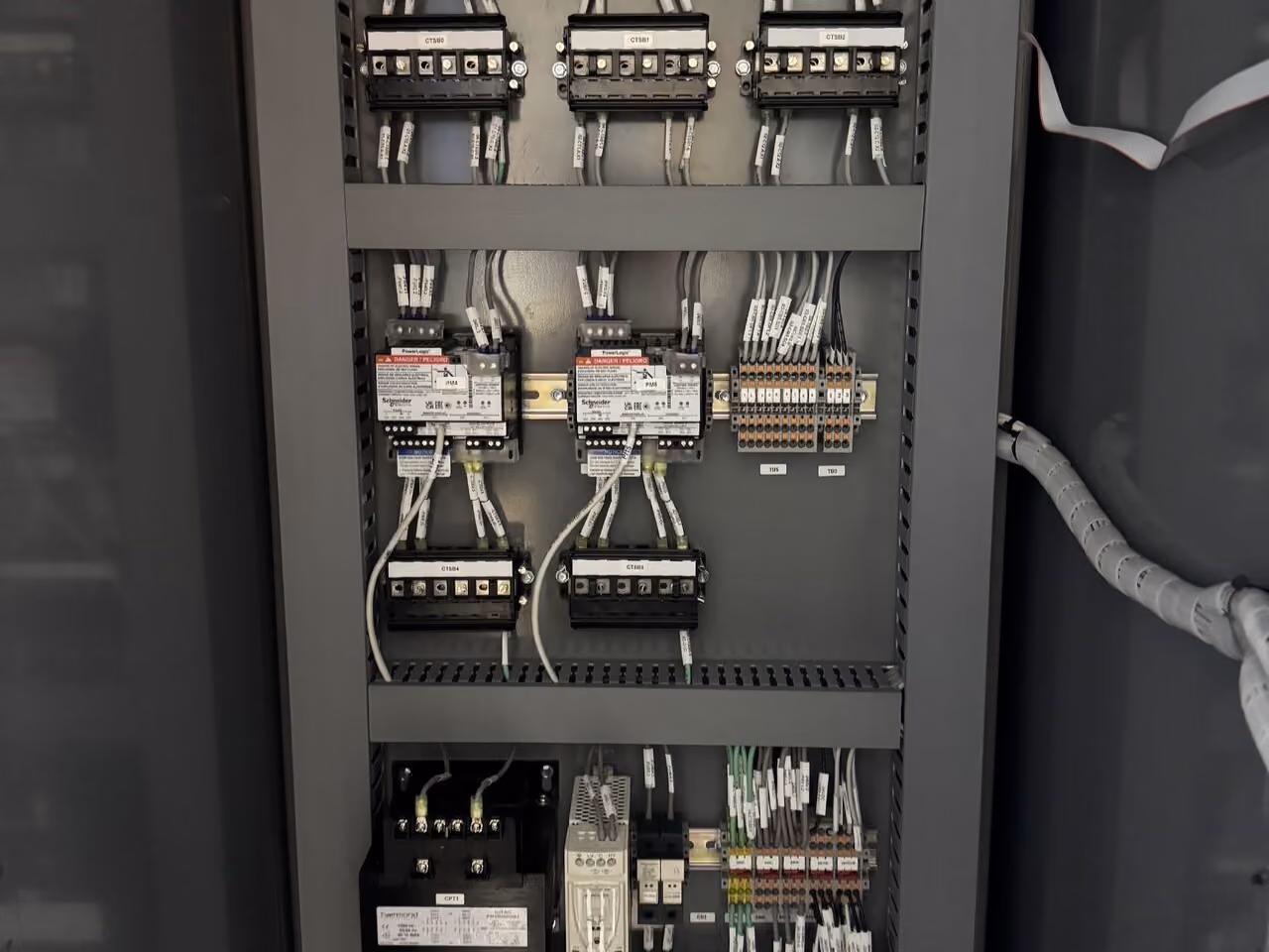 Electrical control panel with organized wiring connected to breakers, relays, and terminals inside a metal enclosure.