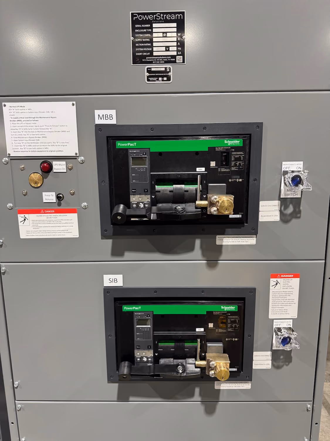 Gray electrical panel with two labeled sections, MBB and SIB, each containing Schneider PowerPact circuit breakers with black frames, green labels, digital displays, and brass components, along with on/off switches and warning labels on either side.